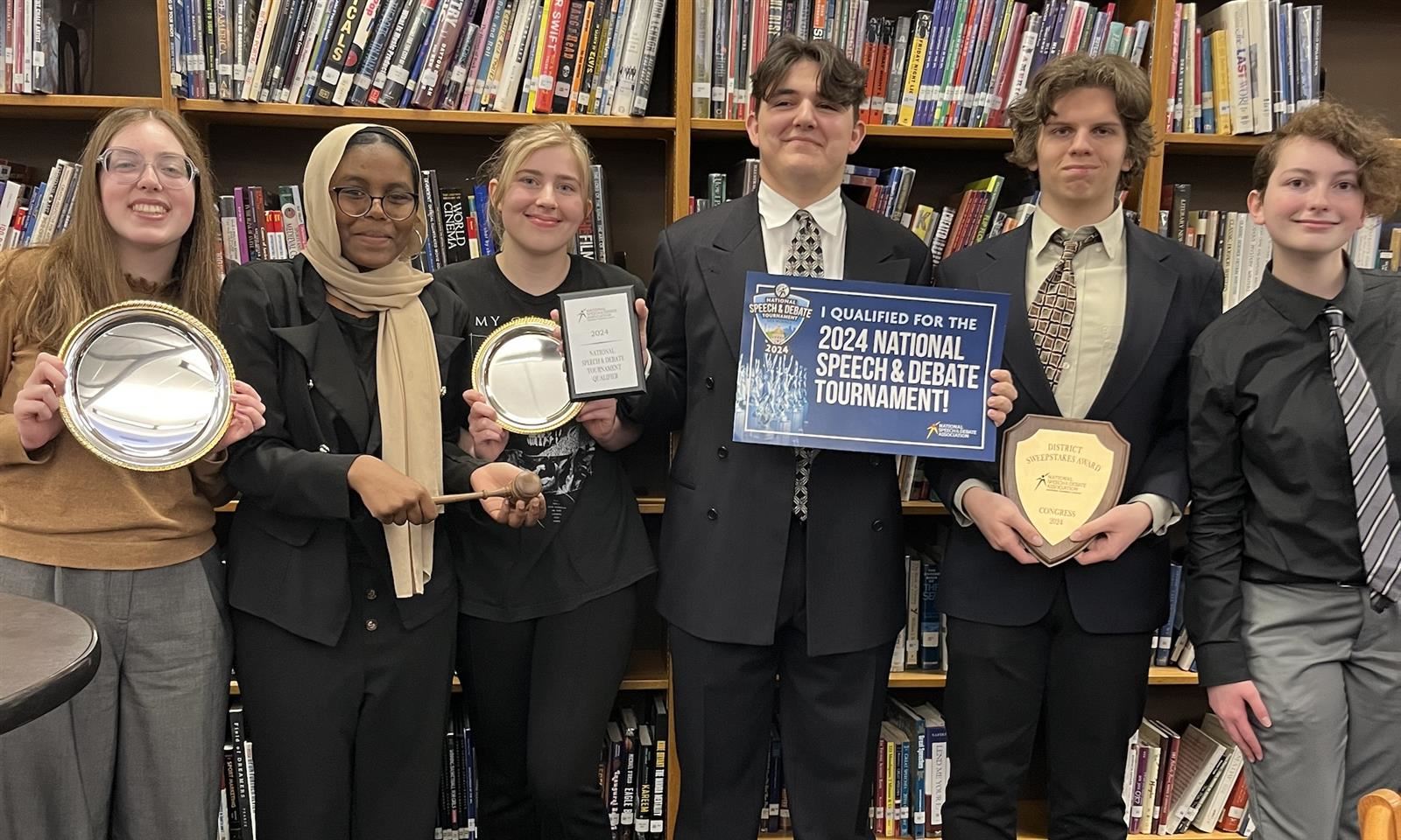 Students smile while holding awards